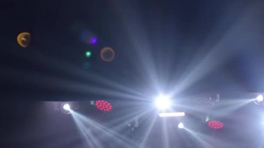 Yoğun spot ışıkları dramatik, yüksek enerjili bir arka plan yaratır. Ana etkinlik, performans veya büyük duyuru kavramı