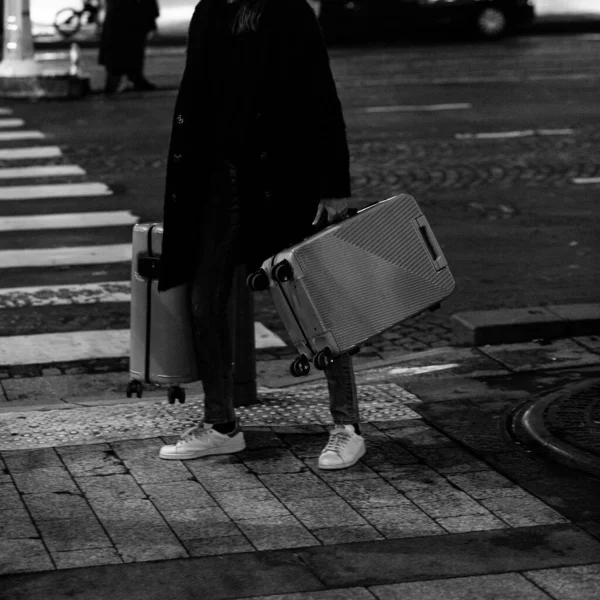 Şık bir gezgin iki bavulla bekliyor. Şehir seyahatleri, yaşam tercihleri ve gizemli ayrılıklar için siyah beyaz bir kavram. Yumuşak odaklanma ve tahıl. Kamera efekti