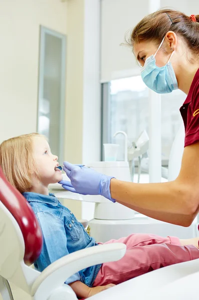 Pediatrische tandarts weinig meisjes tanden in de stoel van de tandartsen te onderzoeken — Stockfoto