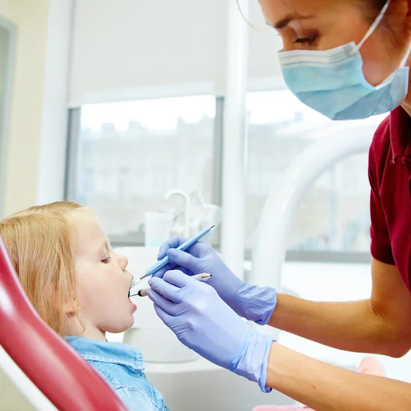 Pediatrische tandarts weinig meisjes tanden in de stoel van de tandartsen te onderzoeken — Stockfoto