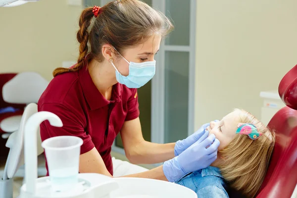 Küçük kızlar diş diş hekimleri sandalyede inceleyerek Pediatrik diş hekimi