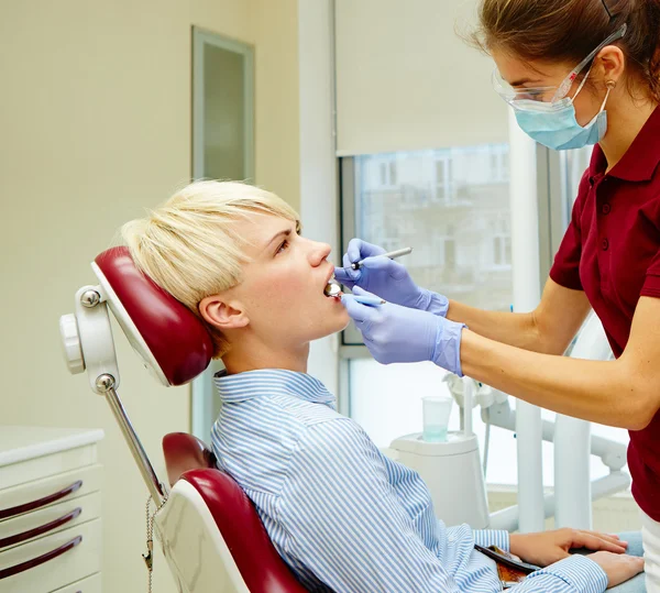 Dentista curando a una paciente femenina — Foto de Stock