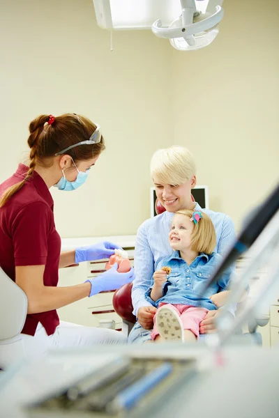 Pediatric dentist explaining to young patient and her mother the model — Stock Photo, Image