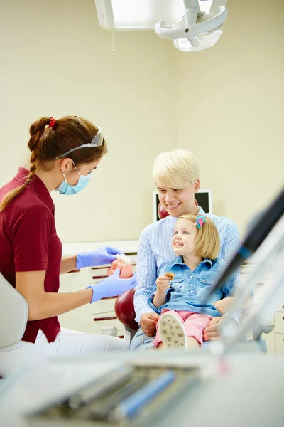 Kinderzahnärztin erklärt der jungen Patientin und ihrer Mutter das Modell — Stockfoto