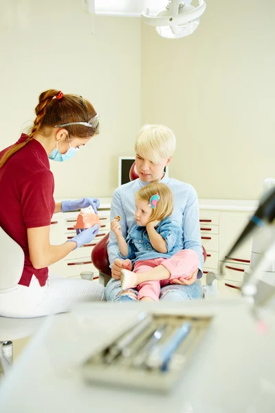 Dentiste pédiatrique expliquant au jeune patient et à sa mère le modèle — Photo