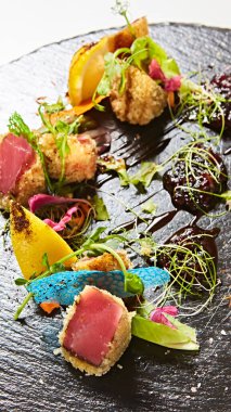 Canlı mercan burçları ve turunçgiller ile kıtır kıtır olmuş gurme kurutulmuş ton balığı, zengin taktiklere ve hayattan daha büyük mutfak dokularına vurgu yapan çok duyusal görsel bir deneyim..