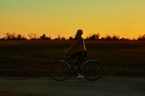 Rowerzysta dziewczyna o zachodzie słońca — Zdjęcie stockowe