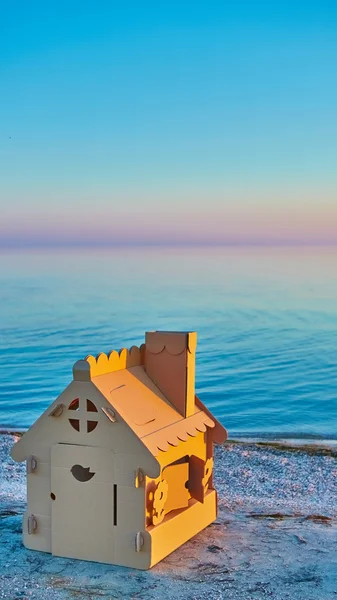Casa giocattolo in cartone ondulato nella costa del mare al tramonto . — Foto Stock