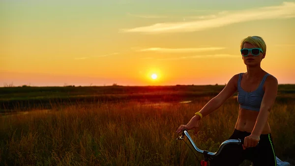 Rowerzysta dziewczyna o zachodzie słońca — Zdjęcie stockowe