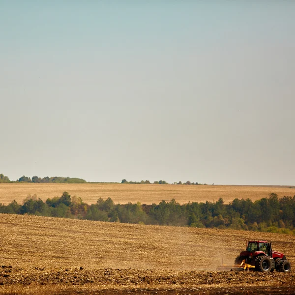 Agrarische landschap. Trekker werken op het veld. — Stockfoto