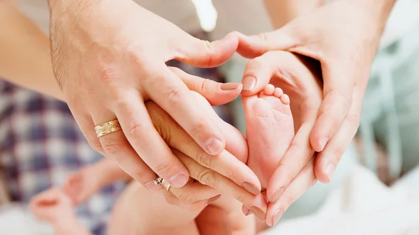 Kinderfüße in den Händen von Mutter und Vater. — Stockfoto