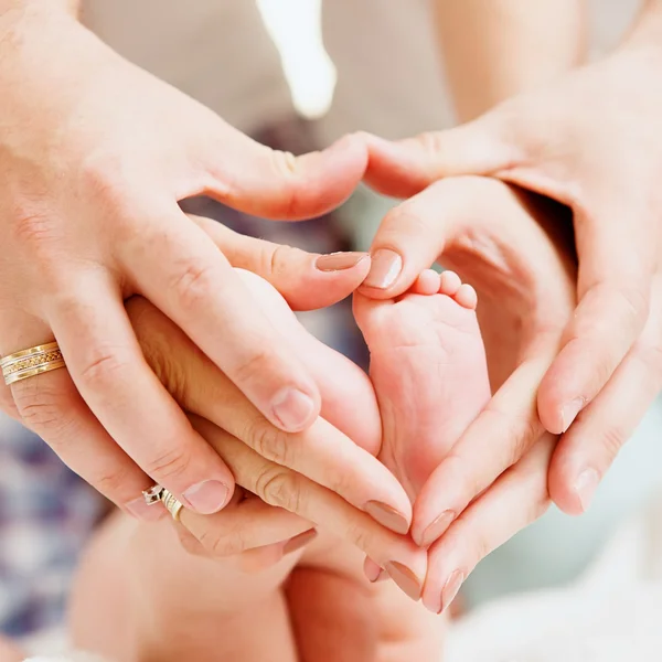 Los pies de los niños en manos de la madre y el padre . — Foto de Stock