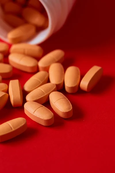 Pills spilling out of pill bottle on red. Top view with copy space. — Stock Photo, Image