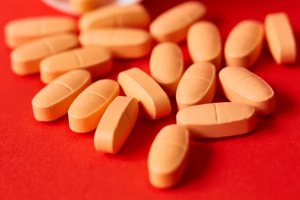 Pills spilling out of pill bottle on red. Top view with copy space. — Stock Photo, Image