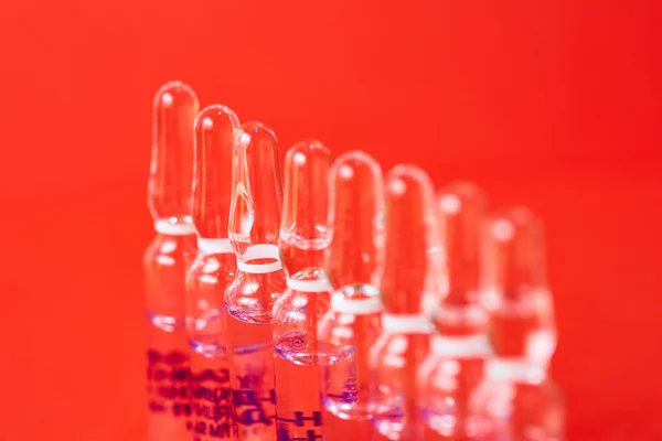 Medizinische Ampullen auf rotem Hintergrund, selektiver Fokus. — Stockfoto