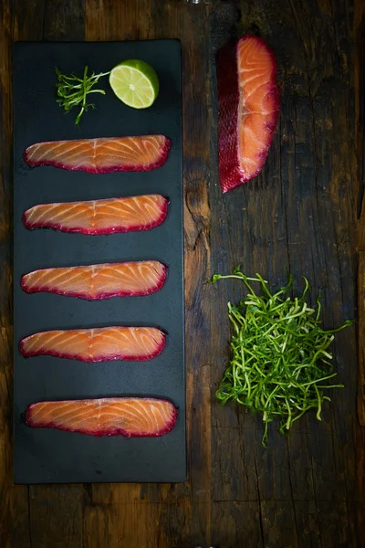 Lachsfilet in Scheiben geschnitten, mit Rote-Bete-Saft über schwarzer Schieferoberfläche angebraten. — Stockfoto