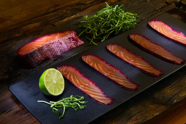 Filete de salmón rebanado, salteado con jugo de remolacha sobre la superficie de pizarra negra . —  Fotos de Stock