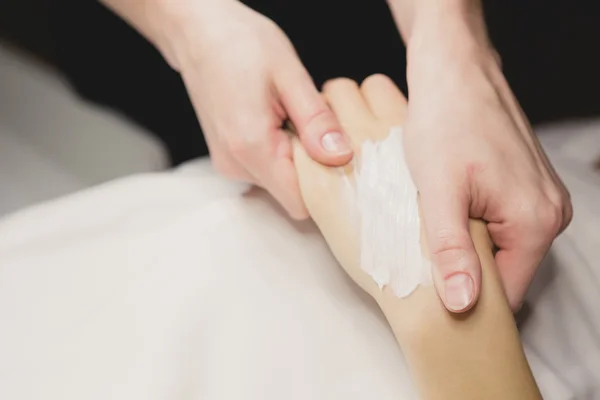 Primer plano de las manos aplicando crema sobre la mesa — Foto de Stock