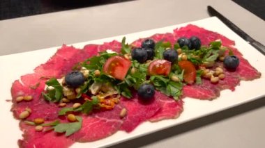 Güzel servis edilmiş carpaccio eti roka, domates, yabanmersini ve tohumlu..