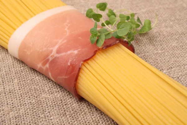 Sheaf raw spaghetti wrapped in bacon with oregano — Stock Photo, Image