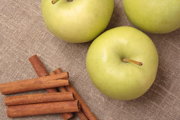 Ripe green apple with cinnamon sticks — Stock Photo, Image