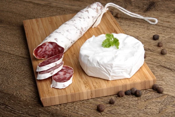 Traditioneel gesneden salami op een houten bord met brie Camembert — Stockfoto