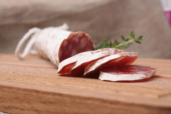 Salami slicing with thyme on board — Stock Photo, Image