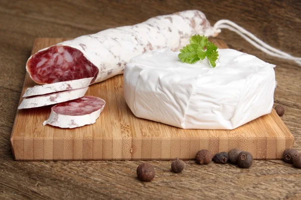 Traditional sliced salami on wooden board with brie Camembert — Stock Photo, Image