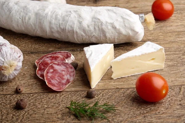 Traditional sliced salami on wooden board with brie Camembert — Stock Photo, Image
