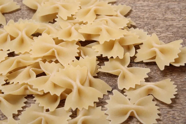 Holztisch mit Mehl Farfalle Nudeln — Stockfoto