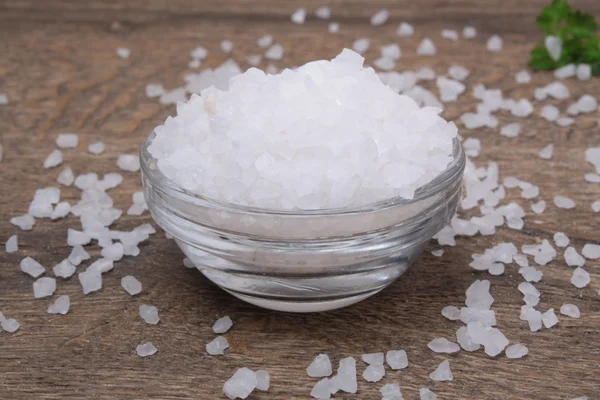 Sea salt in bowl on wooden background — Stock Photo, Image