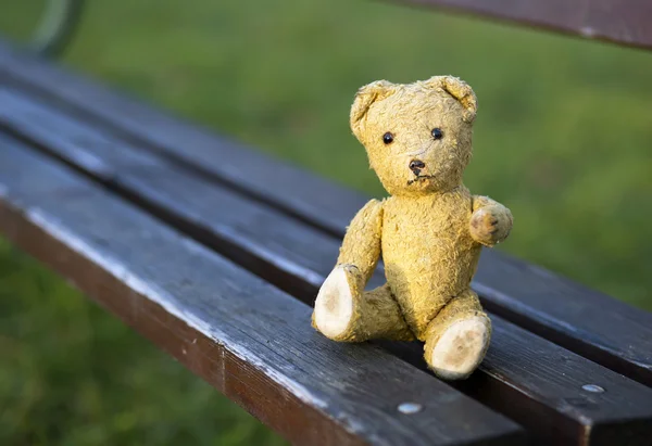 Urso de brinquedo sentado em um banco — Fotografia de Stock
