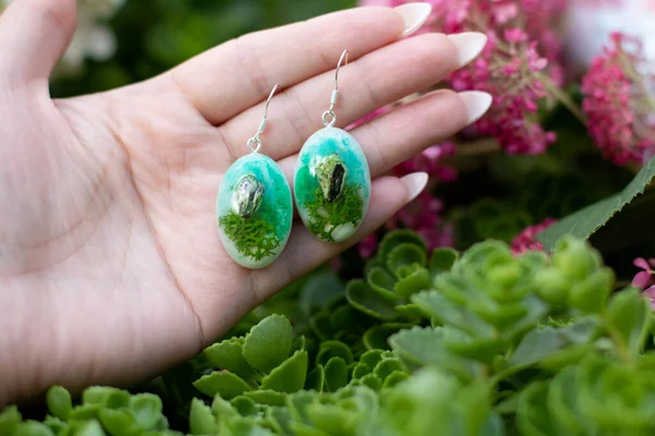 Avucundaki sevimli epoksi reçine küpeler.