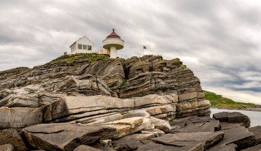 Tarihi deniz feneri, Rennesoy kommune, Stavanger, Norveç, Mayıs 2018 'de jeolojik kaya katmanları oluşumlarıyla Fjoloy adası kıyıları