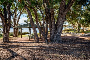 Shaded gazebo under eucalypt canopy beside Canning River in Rossmoyne suburb, Perth, Australia, 16 March 2021