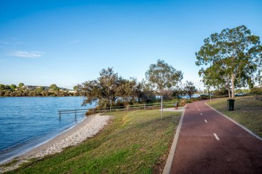 Rossmoyne banliyösü Perth, Avustralya, 16 Mart 2021 'de ağaçlarla kumlu Canning Nehri kıyısı boyunca kırmızı yol paylaşıldı.