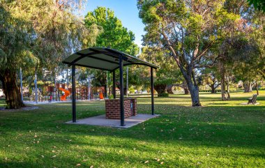 Zeytin Rezervi 'nde güneşli bir günde, 25 Kasım 2021' de Ağaç ve Yeşil Çimenli Çocuk oyun parkının yanındaki Boş Park Piknik Barınağı