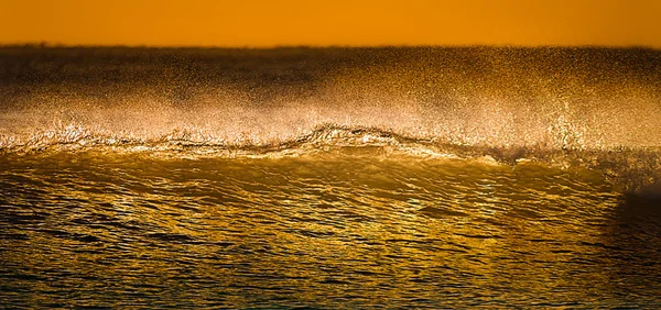 Golden waves breaking at sunset