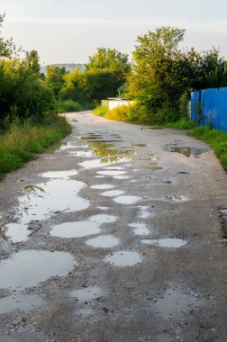Su ile köy yolu üzerinde yağmur sonrası sunset Bulvarında çukur.