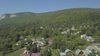 Drone 'un hava görüntüsü. Günbatımında inanılmaz bir sonbahar manzarası. Köyün manzarası, dağ nehri ve dağlar.