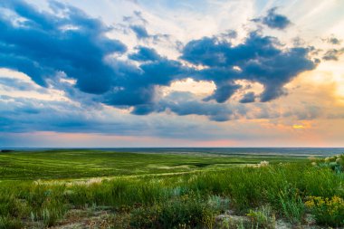 Bozkırda bulutların olduğu manzaralı günbatımı.