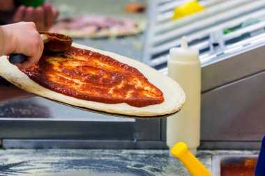 Aşçı mutfakta, pizzanın malzemelerini koyuyor. Pizza konsepti. Gıda üretimi ve teslimatı.