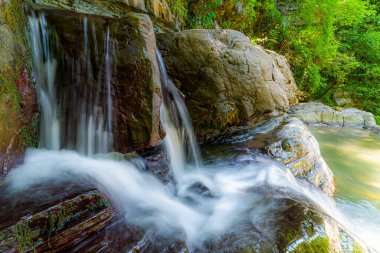 Küçük bir şelalenin ya da büyük taşlı bir akarsuyun uzun pozlama fotoğrafı..