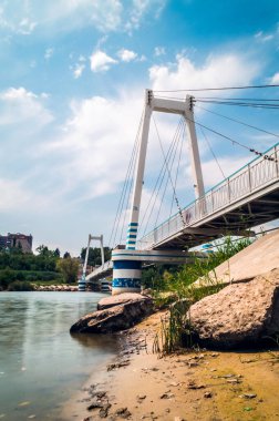 Mavi gökyüzünün altında bulutlu, kablo destekli asma köprü.