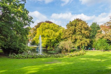 Bruges 'deki Queen Astrid Parkı' nda göl ve çeşmeyle güneşli güzel bir gün. Park şehrin kıyısında yer almaktadır..