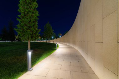 Modern fayans parkında ve duvarın yanındaki taşlarda güzel asfalt yollar var. Akşam vakti, aydınlatma ve park fenerleri..