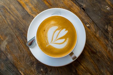 Kahverengi ahşap masada lezzetli bir kapuçino fincanı.