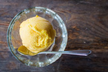Koyu ahşap masada lezzetli renkli dondurmalı cam kase.
