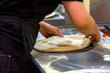 Aşçı mutfakta, pizzanın malzemelerini koyuyor. Pizza konsepti. Gıda üretimi ve teslimatı.