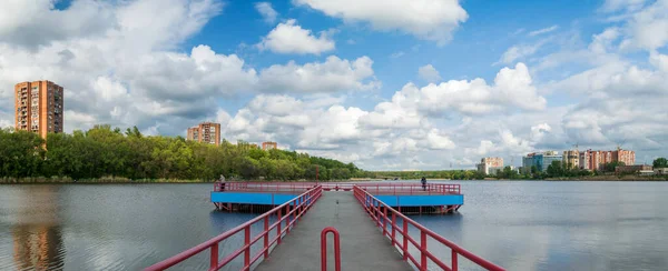 湖の石造りの桟橋 パノラマビュー 風の強い日に湖で高層マンションの建物 青空の上の絵のような雲 — ストック写真